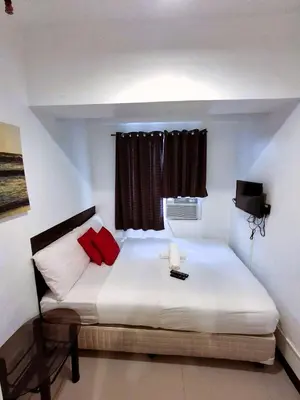 a bedroom with a white bed with red pillows at Makati Poblacion Hotel in Manila