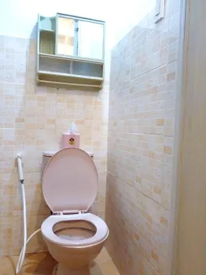 a bathroom with a toilet with a mirror and a window at Makati Poblacion Hotel in Manila