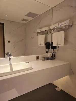 a white bathroom with a sink and a mirror at Bayprime Hotel in Manila