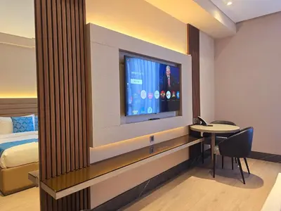 a room with a tv and a bed and a table at Bayprime Hotel in Manila