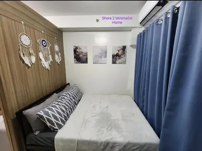 a small bedroom with a bed and blue curtains at SMDC Shore 2 Minimalist Home in Manila