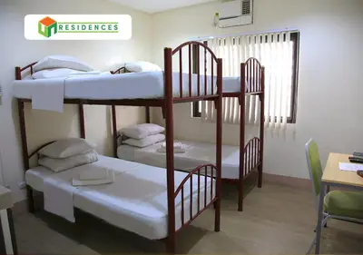 two bunk beds in a room with a table and a desk at UN Residences in Manila