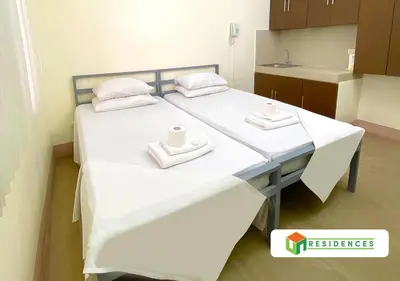 a bed in a room with two towels on it at UN Residences in Manila