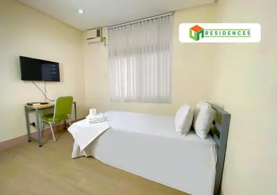 a bedroom with a bed and a desk and a television at UN Residences in Manila