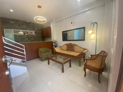 a living room with a staircase and a living room with chairs at ABE Lodge Taguig in Manila