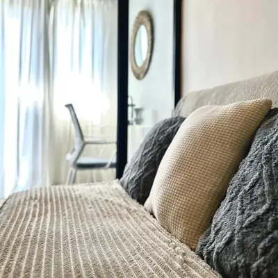 a bed with a pillow and a window with a chair at Evan Suite S Residences T1 in Manila