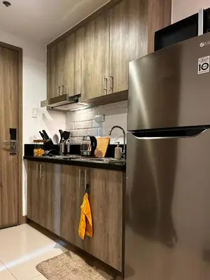 a kitchen with a stainless steel refrigerator and wooden cabinets at Evan Suite S Residences T1 in Manila