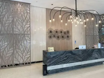 a lobby with a reception desk and a chandelier at Cozy 1 BR One Uptown Residences BGC in Manila