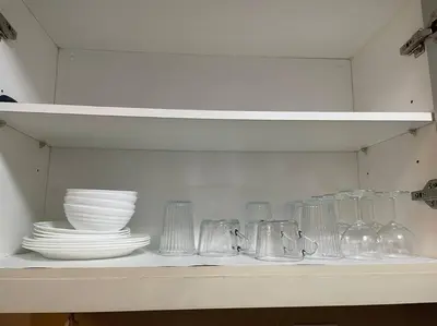 a shelf with dishes and glass items on it at Cozy 1 BR One Uptown Residences BGC in Manila