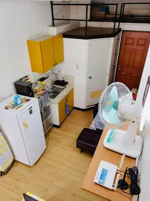 a kitchen with a refrigerator and a table with a fan at Casa Jessica 326 Heavens Place One bedroom plus loft Condo Unit in Bacoor