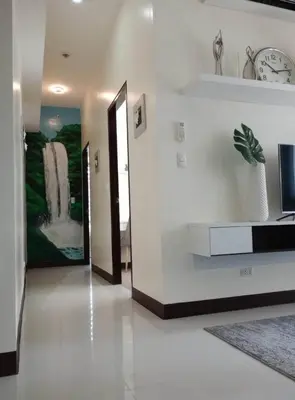 a living room with a clock on the wall at The Florence Condo McKinley Hill in Manila