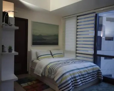 a bedroom with a bed and a large window at The Florence Condo McKinley Hill in Manila