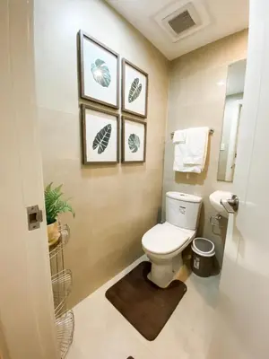 a bathroom with a toilet and three pictures on the wall at The Milano Residences in Manila