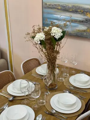 a table with plates and glasses and a vase of flowers at Grand Deluxe 3BR with Bathtub in Uptown BGC in Manila