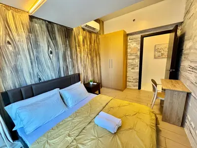 a bedroom with a bed with yellow sheets and a table at Grand Deluxe 3BR with Bathtub in Uptown BGC in Manila