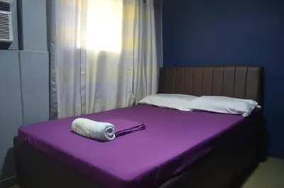 a purple bed with a rolled up towel on it at Gaius Inn in Manila