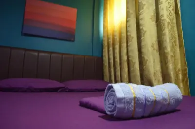 a purple room with purple pillows and a towel at Gaius Inn in Manila