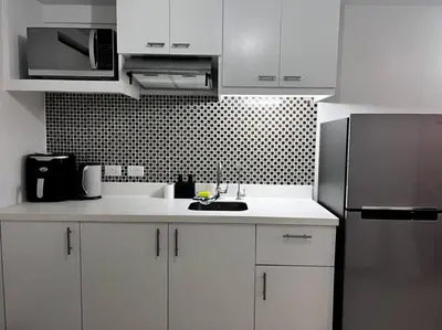 a kitchen with white cabinets and a stainless steel refrigerator at Staycation by JAR - Condo Unit in Manila