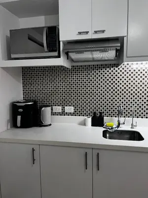 a white kitchen with a sink and a microwave at Staycation by JAR - Condo Unit in Manila