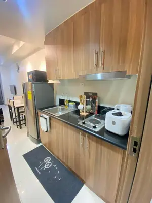 a small kitchen with wooden cabinets and a refrigerator at Jejo Suite Home Shore 3 Residences Staycation 1 BR Unit Near MOA with Netflix and Prime Video in Manila