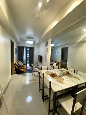 a dining room with a table and a living room at Jejo Suite Home Shore 3 Residences Staycation 1 BR Unit Near MOA with Netflix and Prime Video in Manila