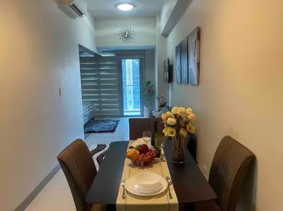 a dining room table with a vase of flowers on it at Luxe 1BR w/ Balcony @ Uptown Parksuites in Manila