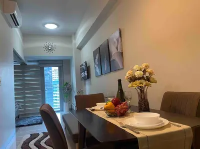 a dining room with a table with a vase of fruit on it at Luxe 1BR w/ Balcony @ Uptown Parksuites in Manila