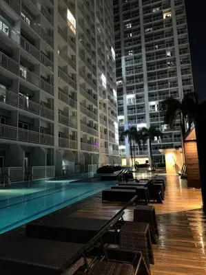 a large building with a swimming pool at night at Night Blink Staycation and Rentals in Manila