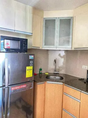 a kitchen with a stainless steel refrigerator and wooden cabinets at One Palm and Two Palm Tree Villas in Manila