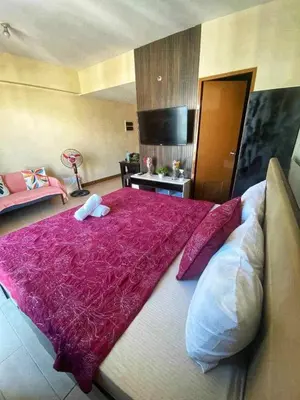a large bed with a red blanket on top of it at Palm Tree Villas in Manila
