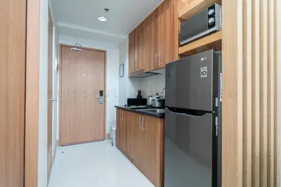 a kitchen with a black refrigerator and wooden cabinets at Blissful Haven Suite Staycation Pasay Metro Manila near SM Mall of Asia Naia Airport Okada in Manila