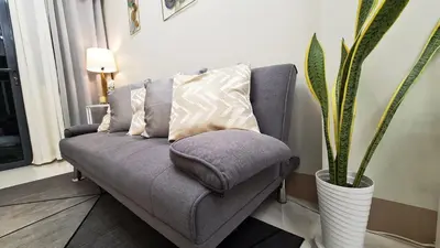 a gray couch with pillows in a living room with a plant at Blissful Haven Suite Staycation Pasay Metro Manila near SM Mall of Asia Naia Airport Okada in Manila
