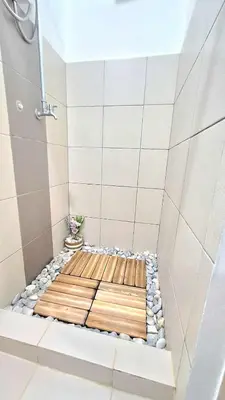 a shower with a wooden seat in a bathroom at Bright and Cozy 1 Bedroom with Balcony Pool View and WiFi in Grace Residences in Manila