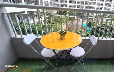 a table and chairs on a balcony with a potted plant at Bright and Cozy 1 Bedroom with Balcony Pool View and WiFi in Grace Residences in Manila