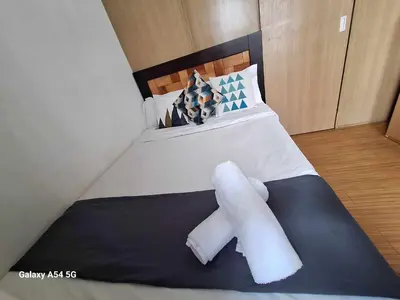 a bedroom with a bed with two towels on it at Bright and Cozy 1 Bedroom with Balcony Pool View and WiFi in Grace Residences in Manila