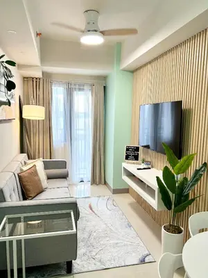 a living room with a couch and a flat screen tv at ClaySky Staycation Cozy Modern 1BR unit near MOA with Netflix & HBO Max in Manila