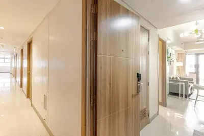 a hallway with a wooden door and a living room at ClaySky Staycation Cozy Modern 1BR unit near MOA with Netflix & HBO Max in Manila
