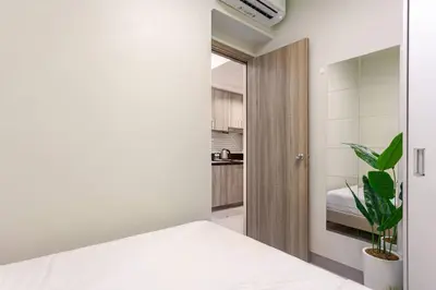 a bedroom with a white bed and a plant at ClaySky Staycation Cozy Modern 1BR unit near MOA with Netflix & HBO Max in Manila