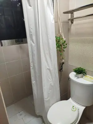 a bathroom with a toilet with a shower curtain at 2-BR COZY condo 200mbpsFiberWiFi/Netflix/pool/WFH in Manila
