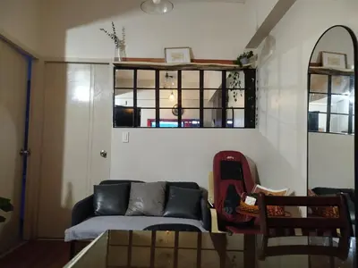 a living room with a couch and a window at 2-BR COZY condo 200mbpsFiberWiFi/Netflix/pool/WFH in Manila