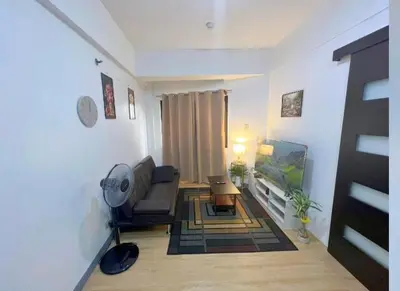 a living room with a couch and a flat screen tv at One Bedroom condo Unit in Eastwood Libis . Fast free wifi /netflix in Manila