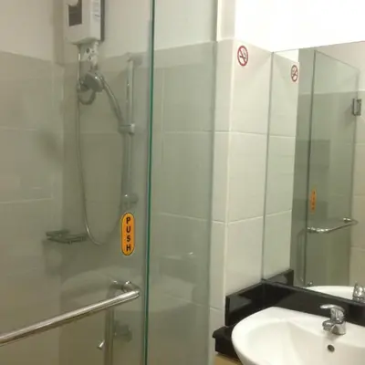 a shower with a glass door next to a sink at Justcondos at Sea Residences in Manila