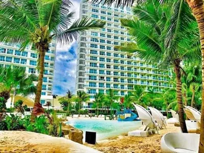 a resort with a pool and palm trees and a building at Metro Manila Cityscape Charm at Azure Urban Resort Paranaque near NAIA Airport in Manila