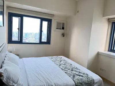 a bedroom with a bed and a window at Grand Riviera Suites in Manila