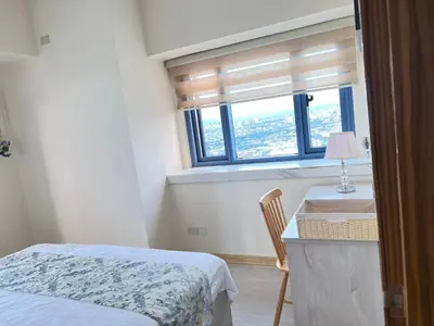 a bedroom with a bed and a desk with a window at Grand Riviera Suites in Manila