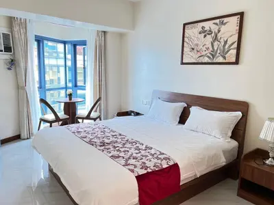 a bedroom with a bed and a table and a window at Grand Riviera Suites in Manila