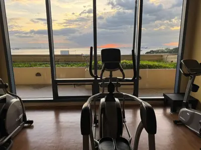 a room with a gym with a view of the ocean at Grand Riviera Suites in Manila