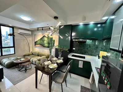 a kitchen and living room with green cabinets and a table at The DRYM Space — Curated Staycation in Mandaluyong in Manila