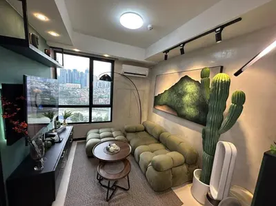 a living room with a couch and a cactus painting at The DRYM Space — Curated Staycation in Mandaluyong in Manila
