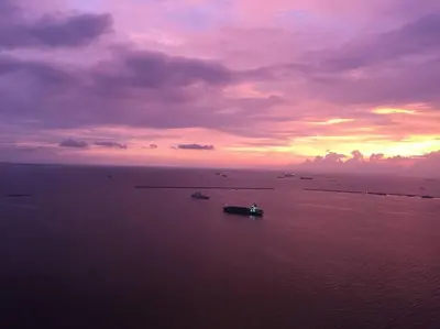 a boat in a body of water with a sunset at Partial Ocean View Opposite the US Embassy in Manila
